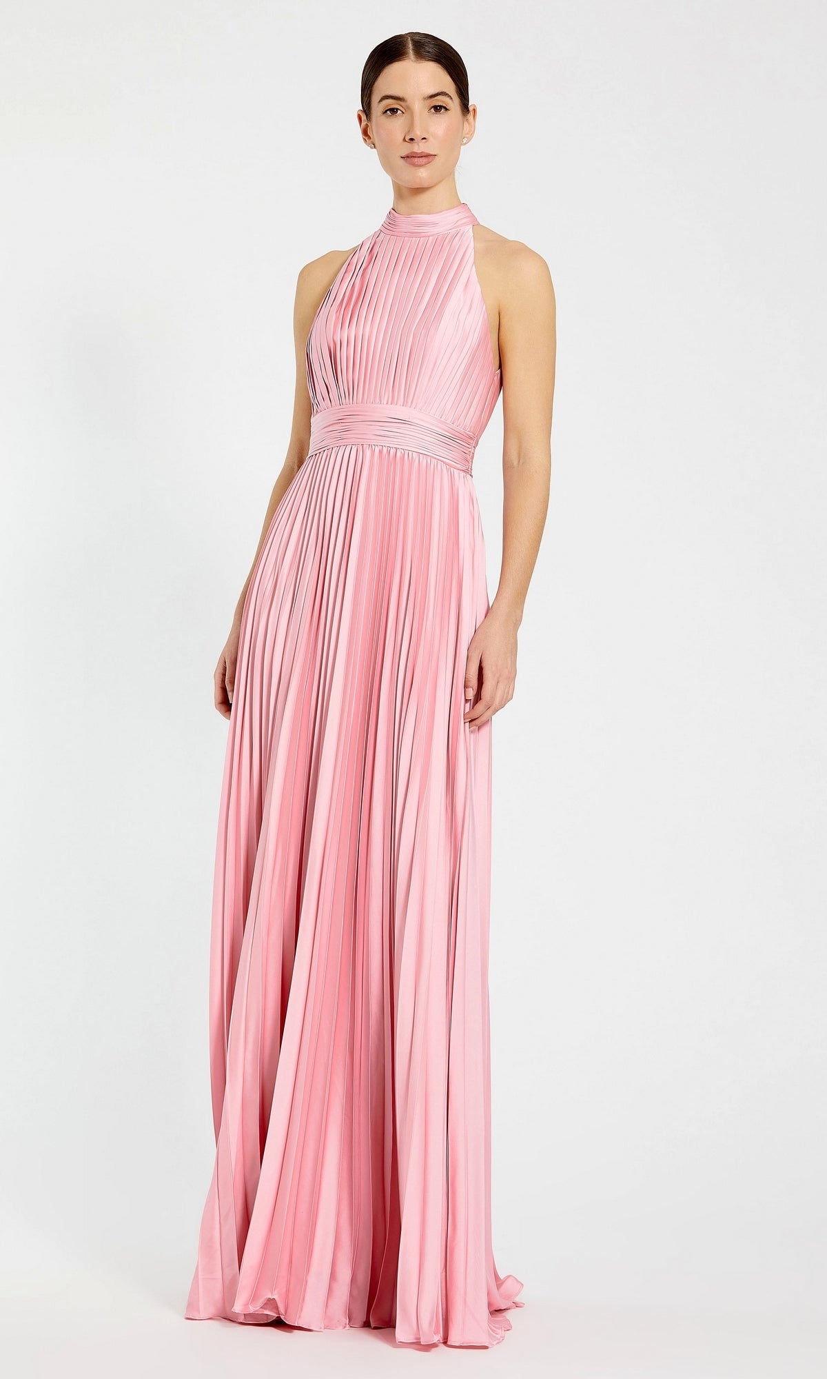 A woman models the Mac Duggal 26992 Long Pleated A-Line Formal Dress—a sleeveless, floor-length pink gown with a high neckline—against a plain white background.